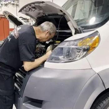 A mechanic in a Winkler Automotive uniform performs fleet service on a commercial vehicle during auto care check up.