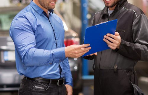 Two men go over printed car diagnostics during auto care check up.