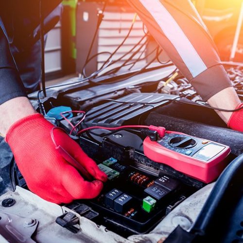 Red-gloved hands inspect the electronics for a vehicle